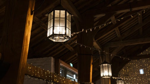 Large hanging lanterns and fairy lights illuminating the beams in the Airedale barn ceiling